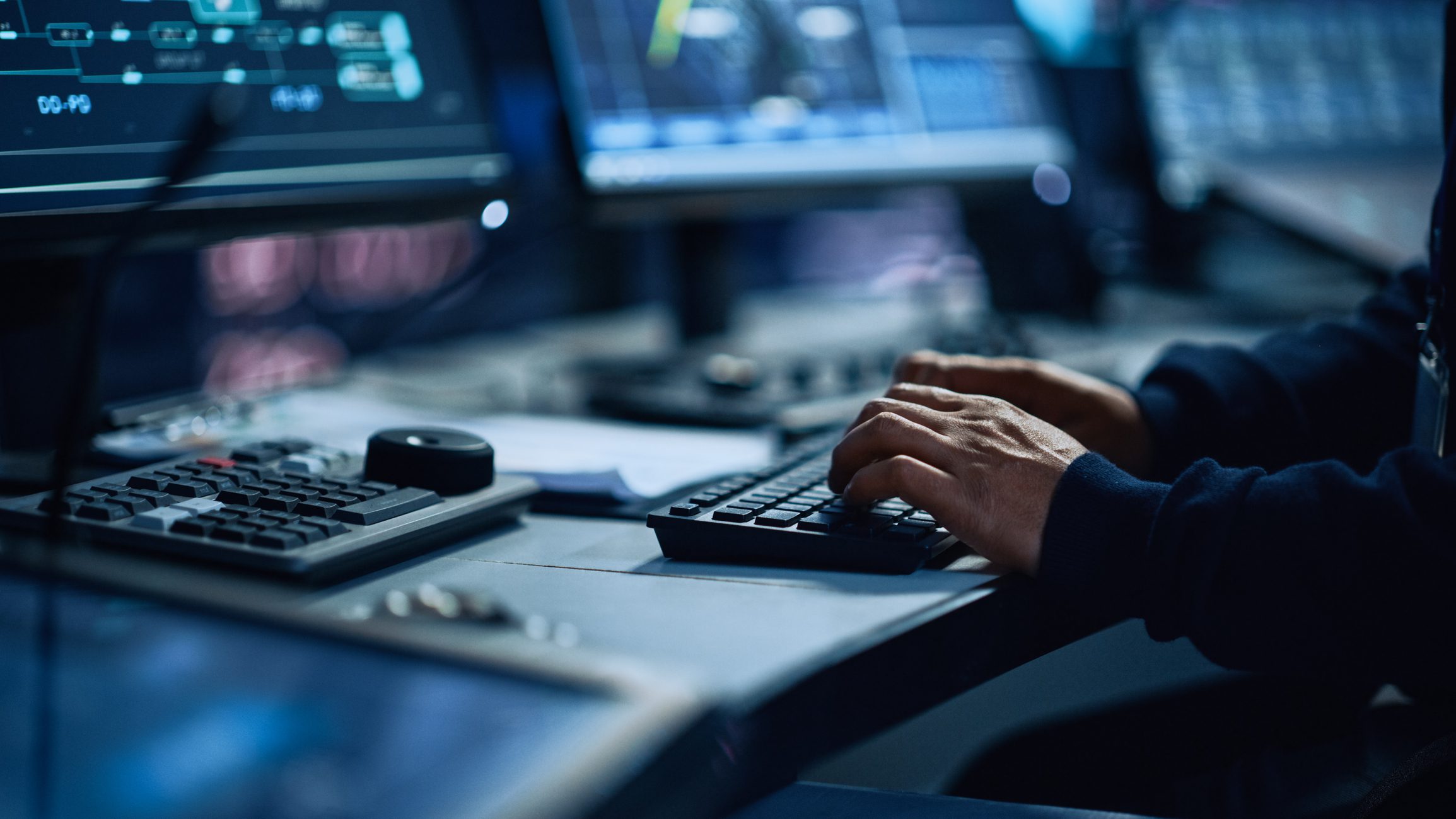 A Photo Realistic Image of a Person’s Hands Typing on a Keyboard in a Control Room