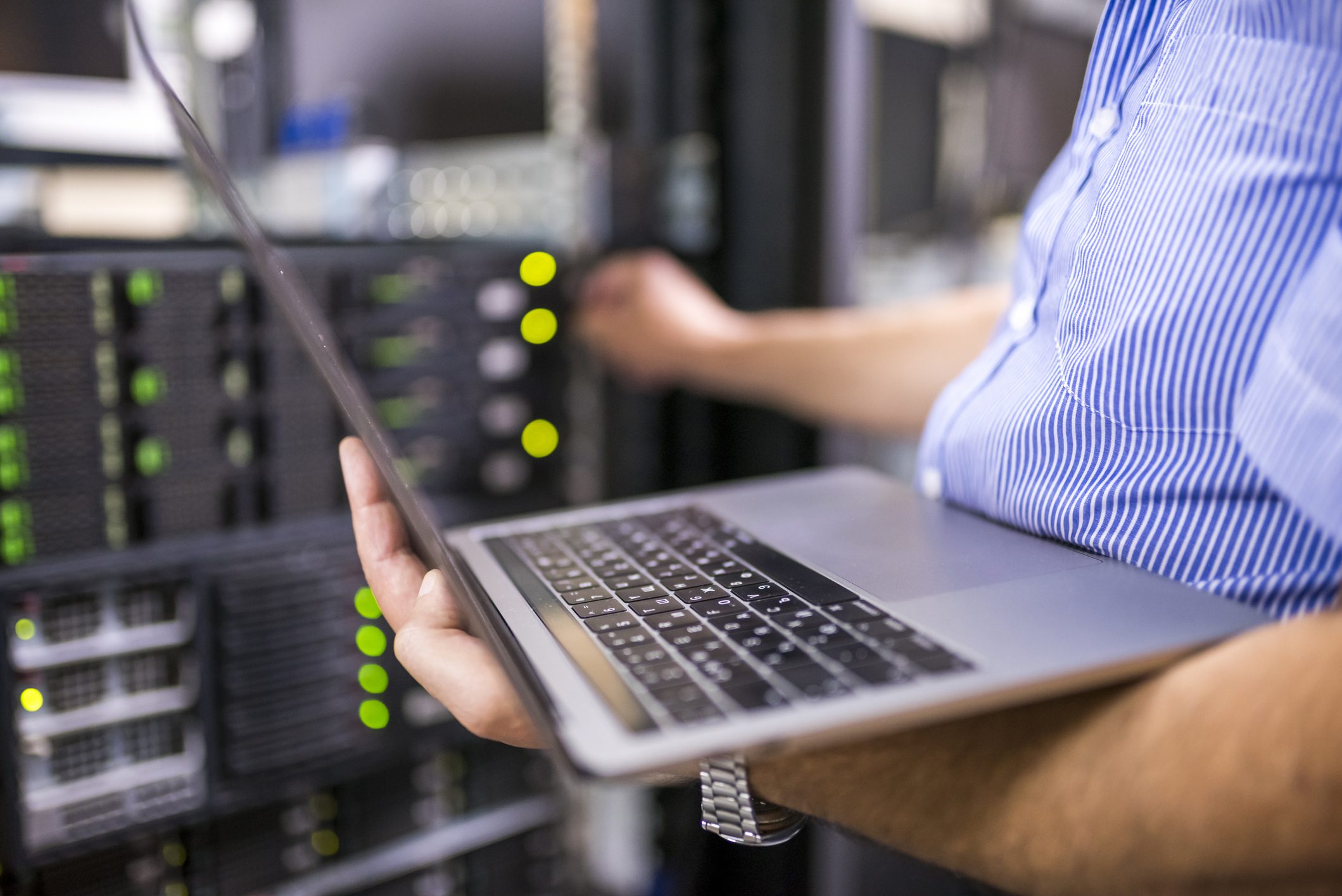A Person Holding a Laptop in Front of a Server Rack
